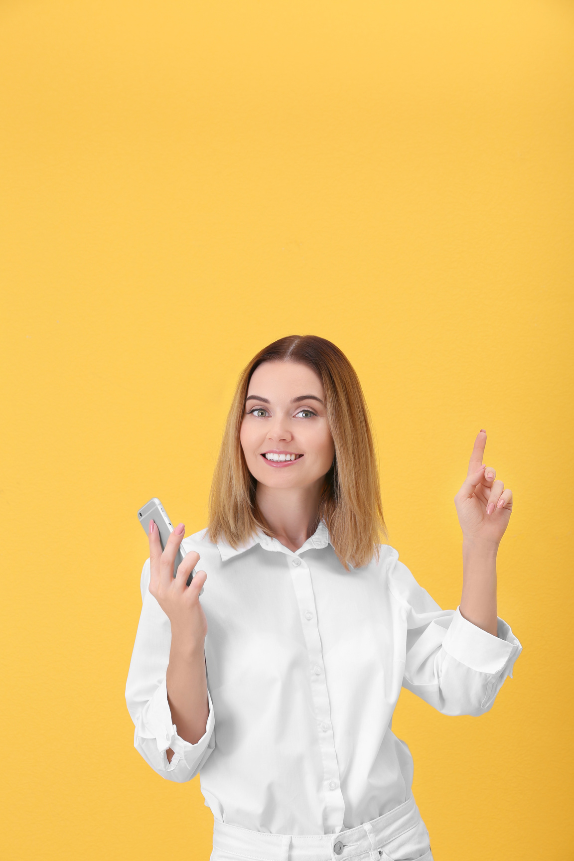 Young Woman Using Cell Phone on Yellow Background